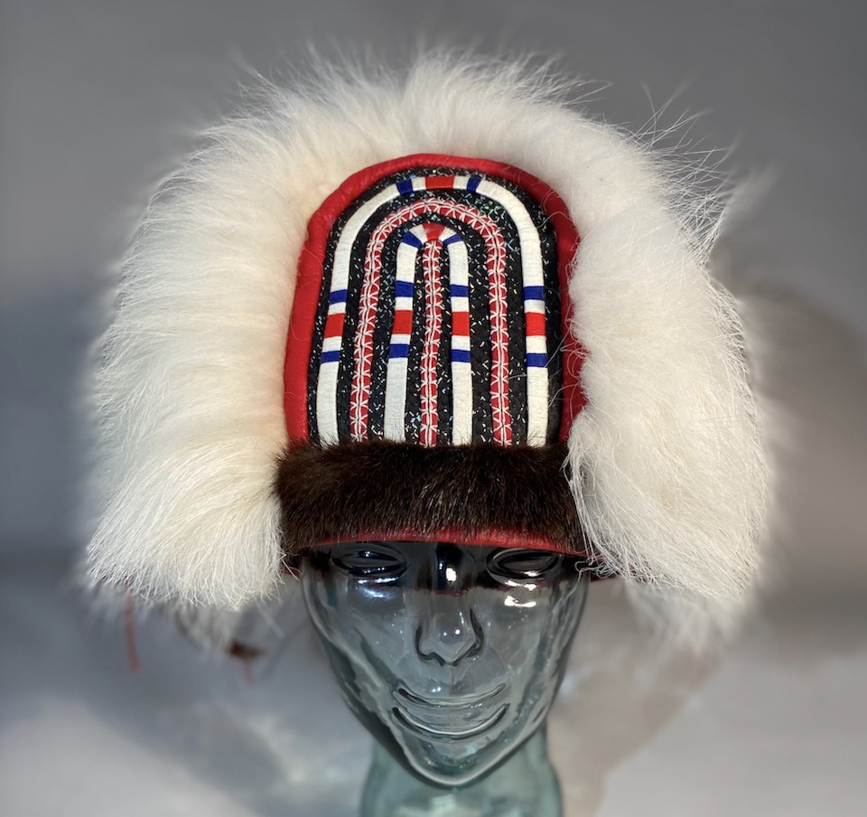 An embroidered fur hat on a glass stand