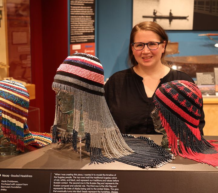 Woman standing behind a display of beaded headdresses